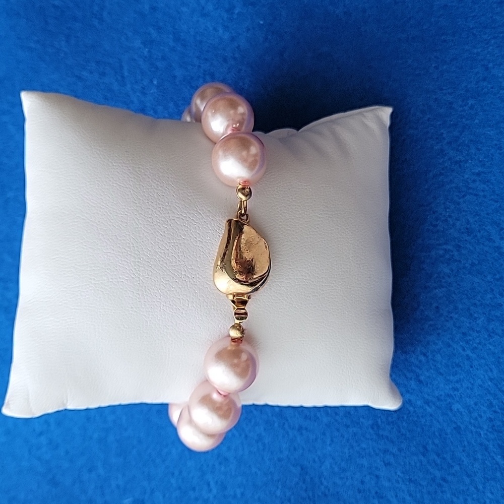 Pink pearl bracelet with open box golden clasp.
